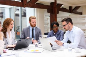 Team of business people is working on new business strategy with a financial analyst while analyzing financial chart during meeting in the office.